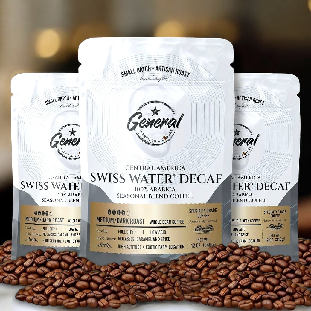 Three bags of General Warfield's Swiss Water Decaf Coffee sitting on fresh decaffeinated coffee beans. 